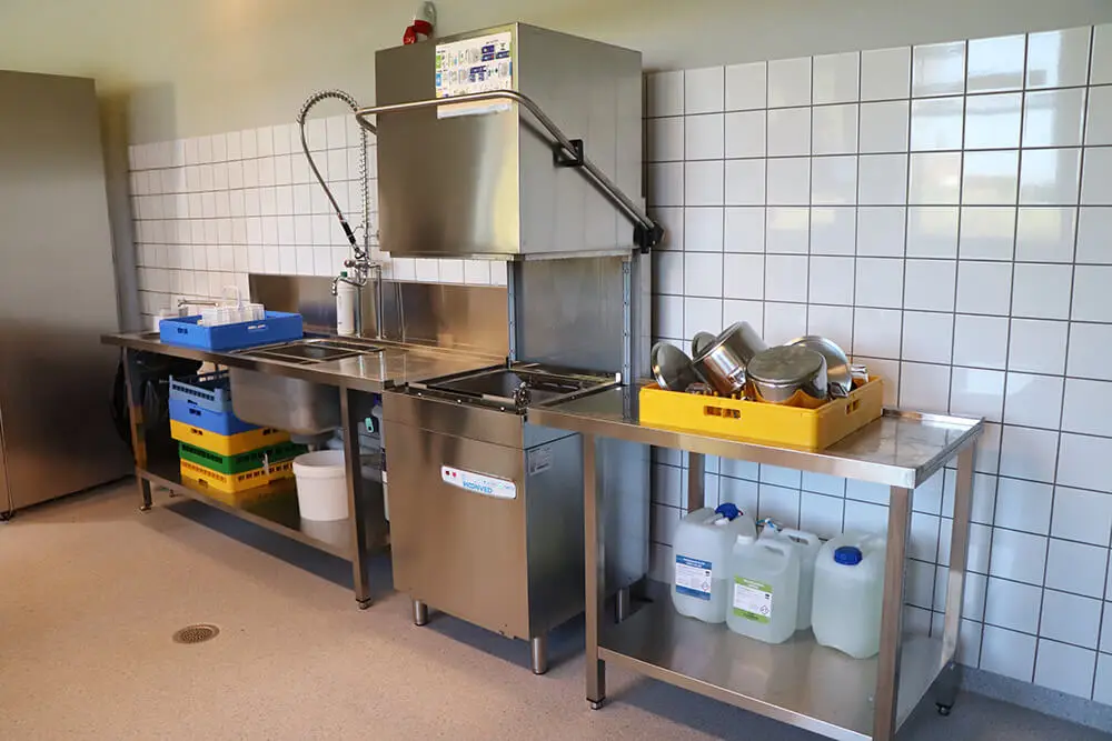 Opvaskeafdeling i et skolek&oslash;kken med et forskyllebord, h&aelig;tteopvaskemaskine og t&oslash;rrebane. 